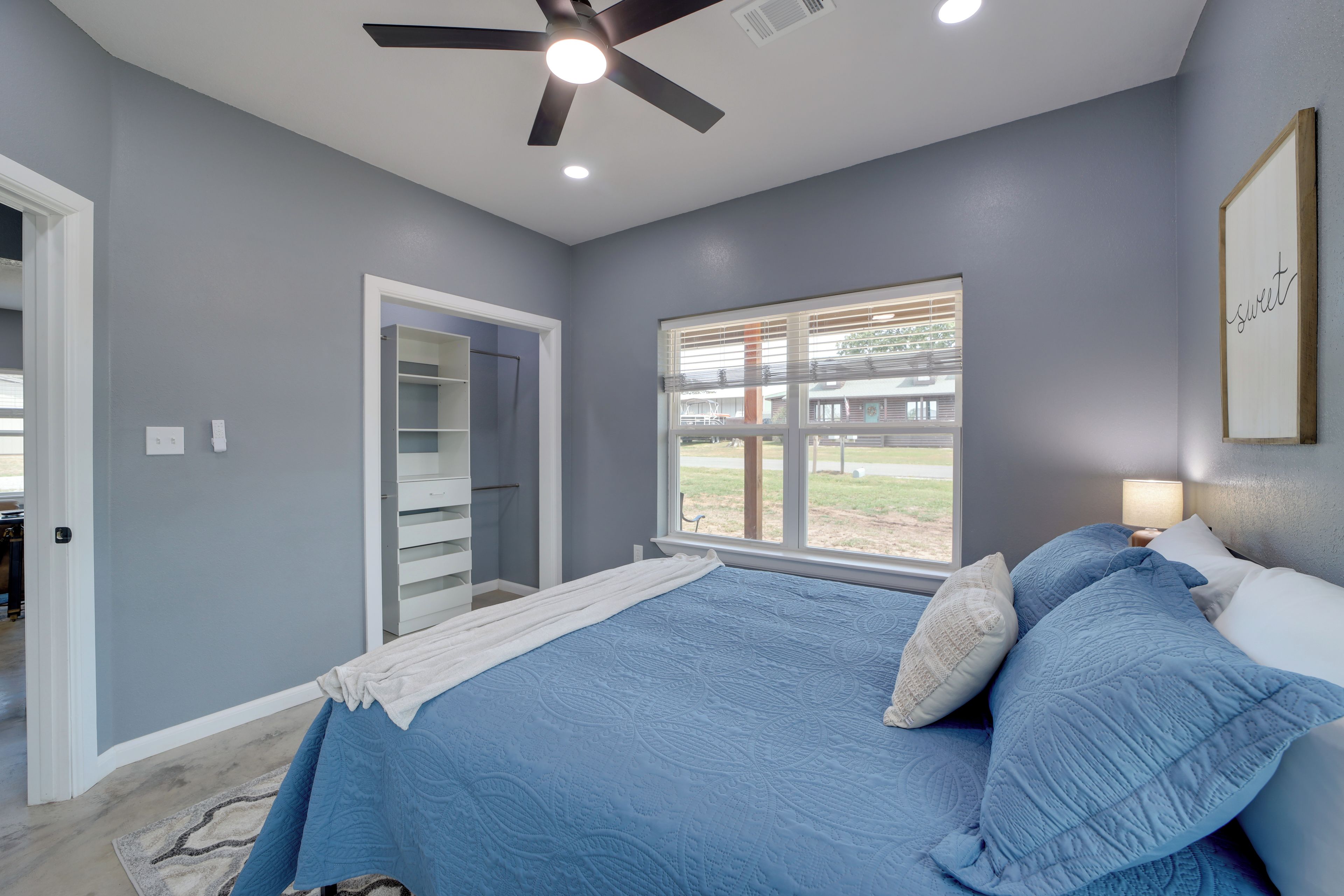 A bedroom with a bed, a ceiling fan, a window with blinds, and a door leading to a closet.