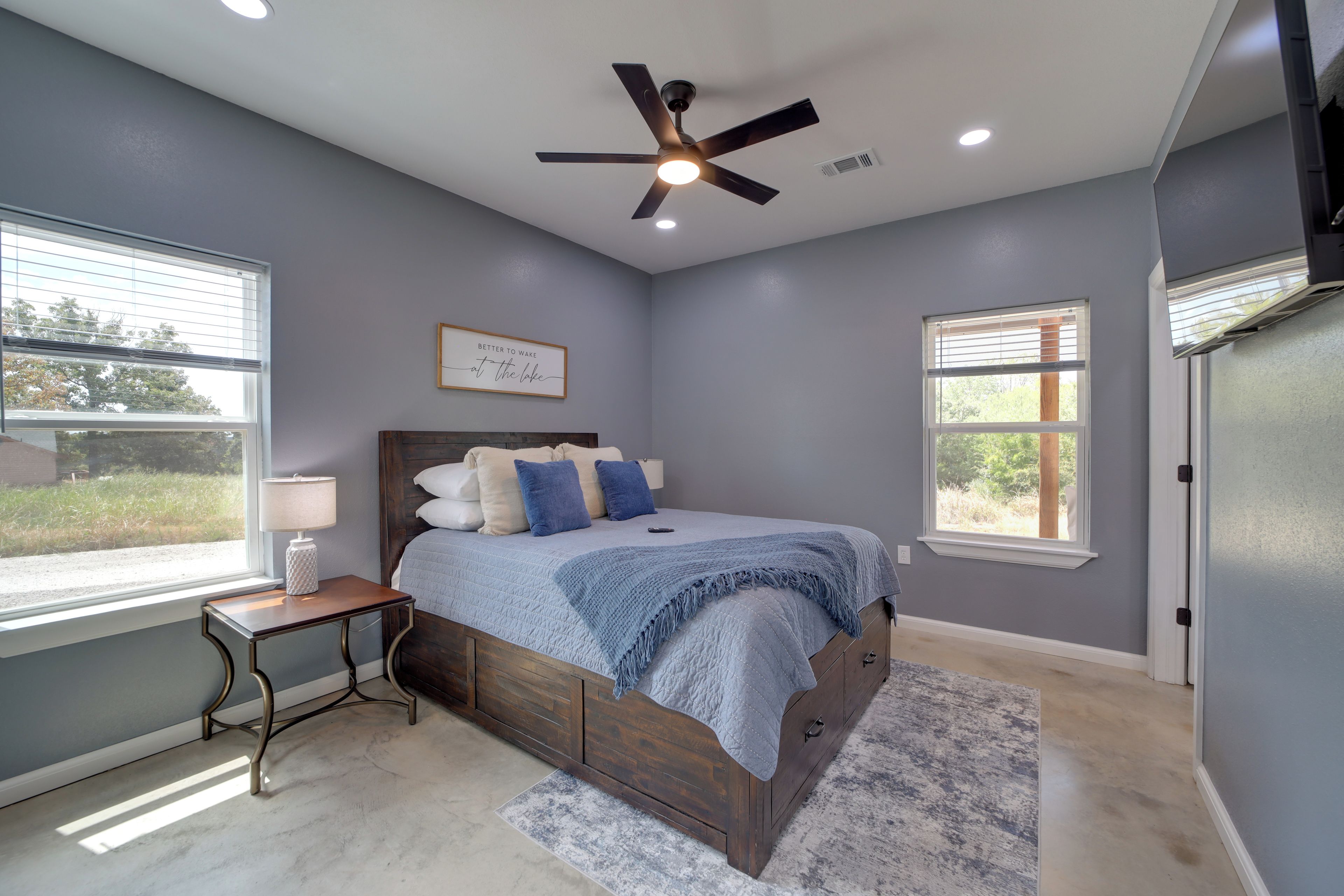 A bedroom with a bed, a nightstand, a ceiling fan, and a window with blinds.