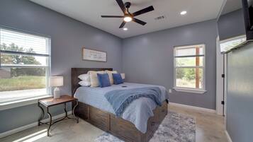 A bedroom with a bed, a nightstand, a ceiling fan, and a window with blinds.