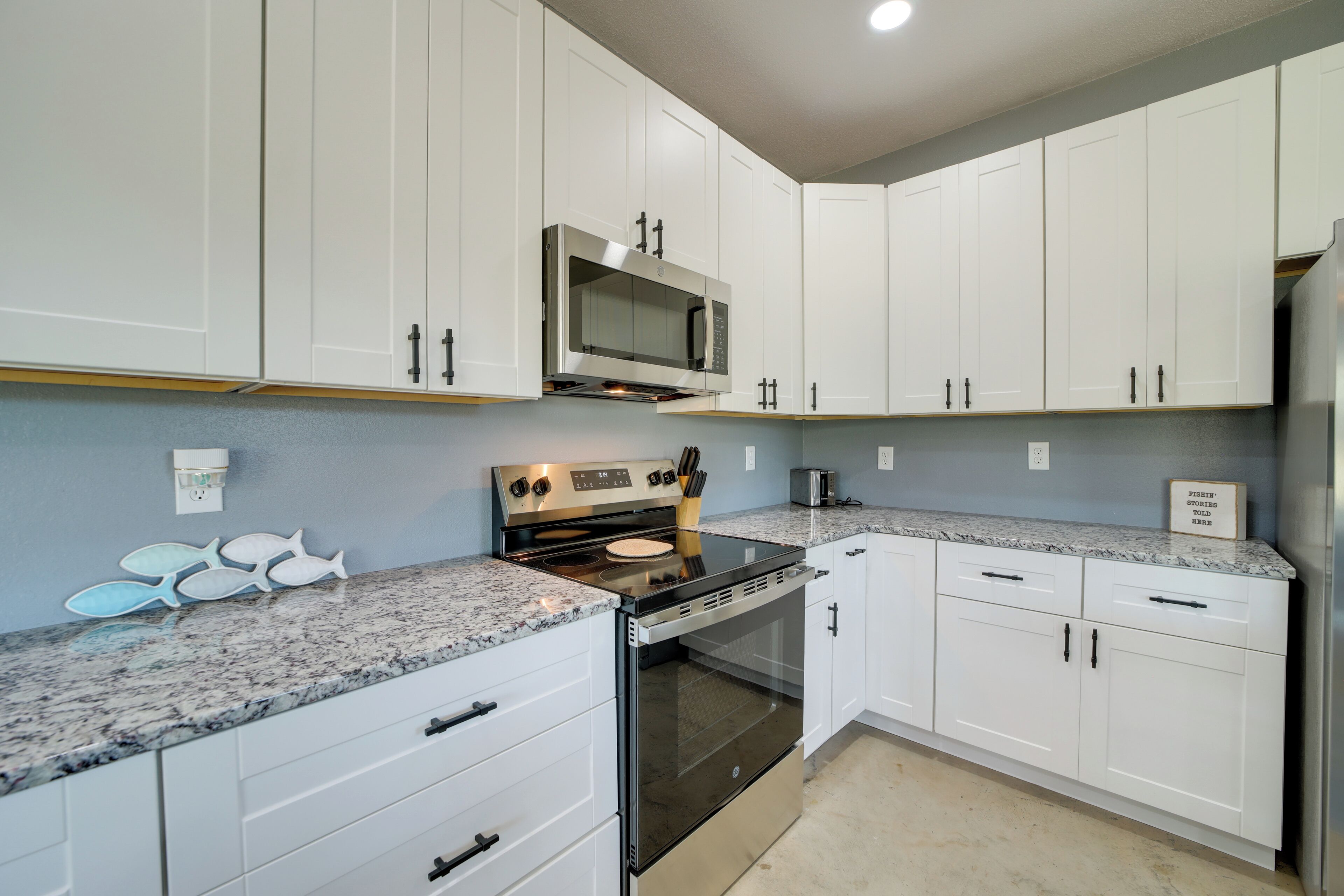 A modern kitchen with white cabinetry, a stainless steel stove, and a microwave.