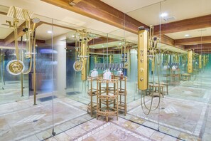 Un baño lujoso con múltiples detalles dorados, incluyendo un espejo grande y una zona de ducha.