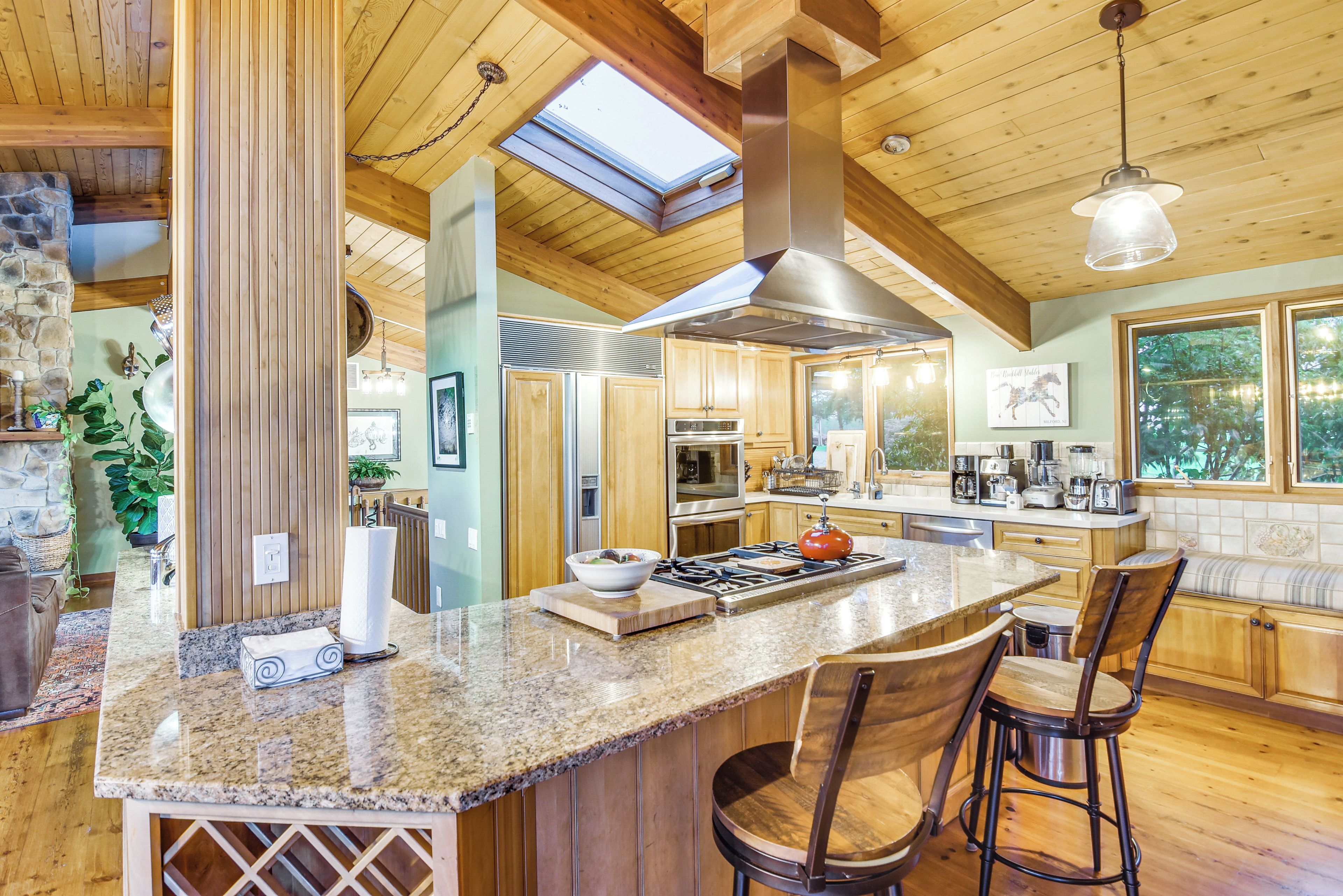 A spacious kitchen with a large island, wooden cabinetry, and a skylight.