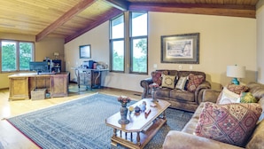 A spacious living room with a high ceiling, large windows, a fireplace, a coffee table, and a comfortable seating area. - 6,000-sq-ft Estate in Delaware River Valley (Milford)