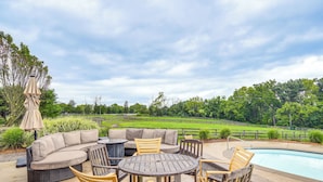 An outdoor patio with a pool, seating area, and a view of a green landscape. - 6,000-sq-ft Estate in Delaware River Valley (Milford)