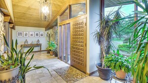 A wooden interior with a chandelier, potted plants, and a view through a glass door. - 6,000-sq-ft Estate in Delaware River Valley (Milford)
