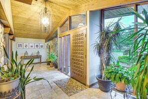 A wooden interior with a chandelier, potted plants, and a view through a glass door. - 6,000-sq-ft Estate in Delaware River Valley (Milford)