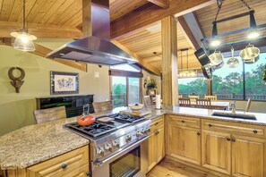 Une cuisine avec des meubles en bois, une cuisinière à gaz et des casseroles suspendues.