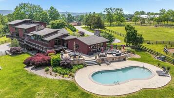 A large, multi-story house with a pool and outdoor seating area.