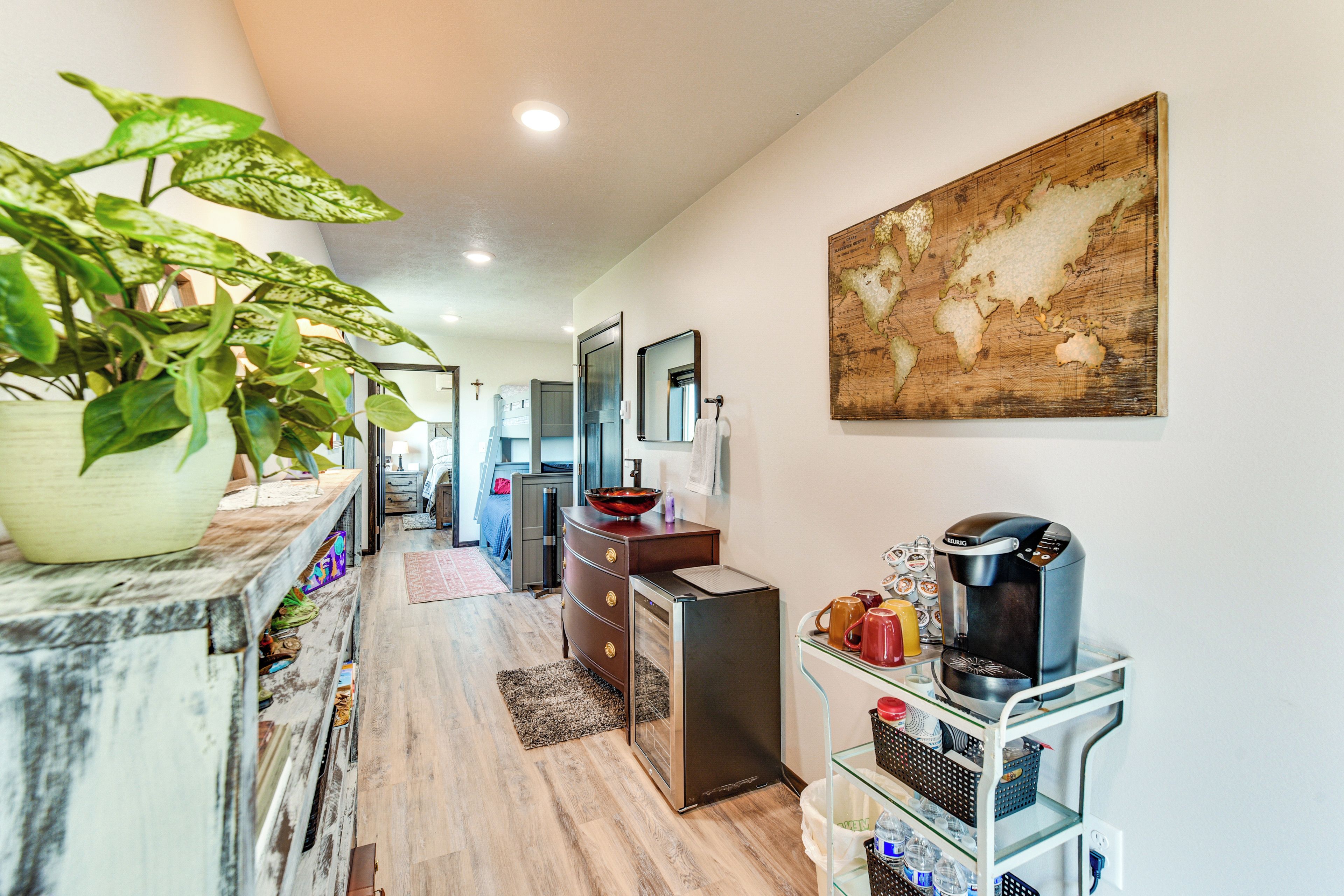 A hallway with a wooden floor, a potted plant, a coffee machine, and a map on the wall.