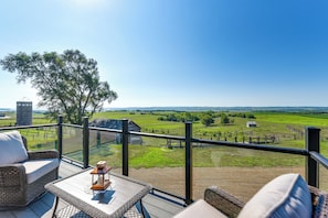 A balcony with wicker furniture, a lantern, and a view of a green landscape. - River Views & Rural Charm: Springfield Retreat (Springfield)