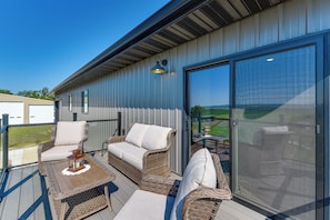 A covered outdoor seating area with wicker furniture and a table, overlooking a landscape. - River Views & Rural Charm: Springfield Retreat (Springfield)
