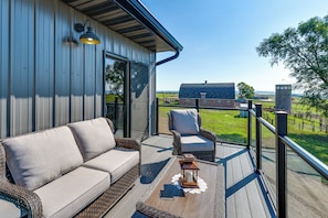 A deck with wicker furniture and a lantern, overlooking a rural landscape.