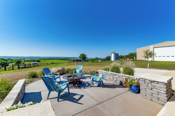 An outdoor patio with a fire pit, seating, and a view of the countryside.