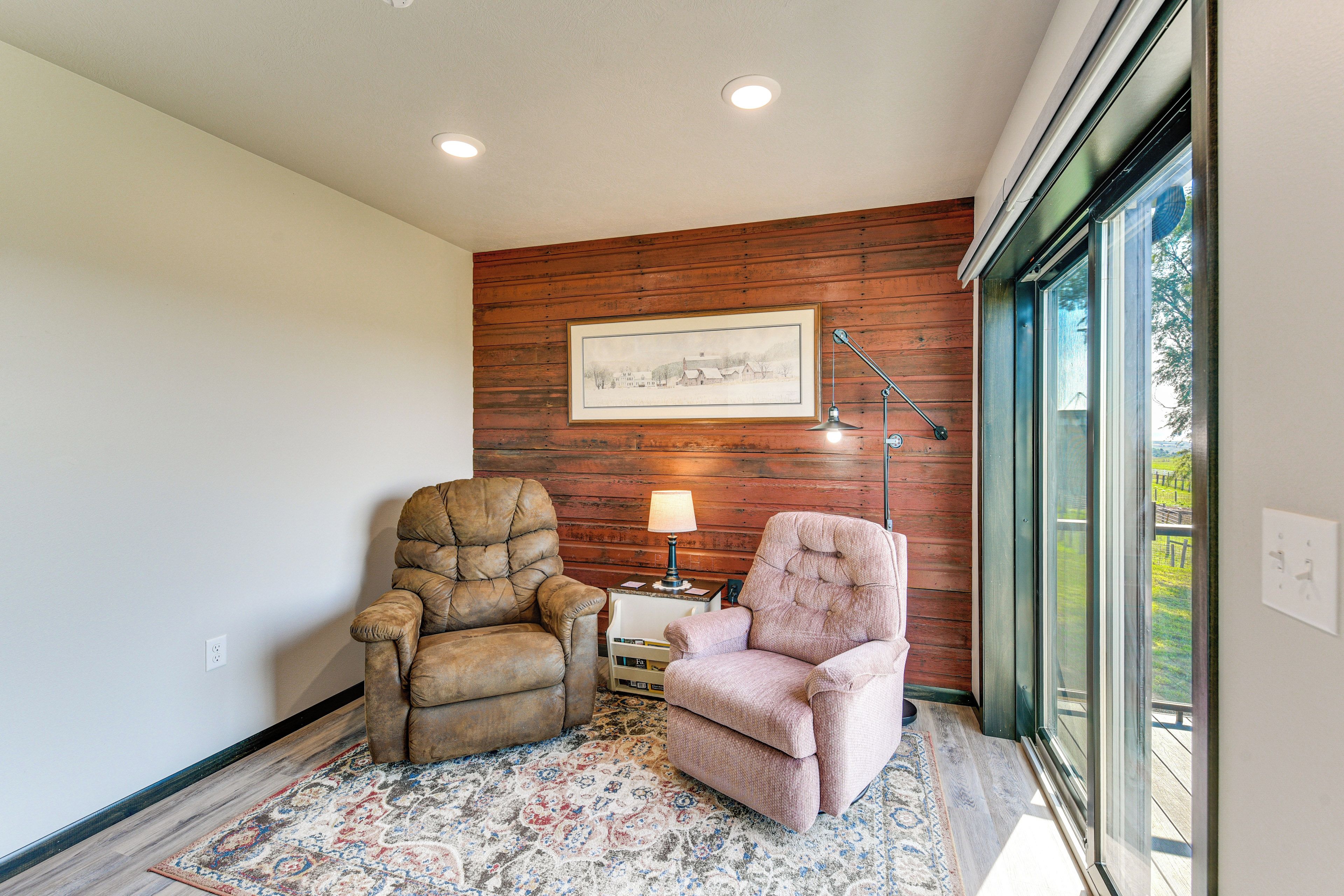 A room with two leather armchairs, a framed picture on the wall, and a lamp on a small table.