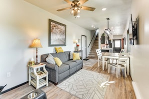 A modern living room with a gray sofa, a dining table with chairs, a staircase leading to a kitchen, and a ceiling fan. - River Views & Rural Charm: Springfield Retreat (Springfield)
