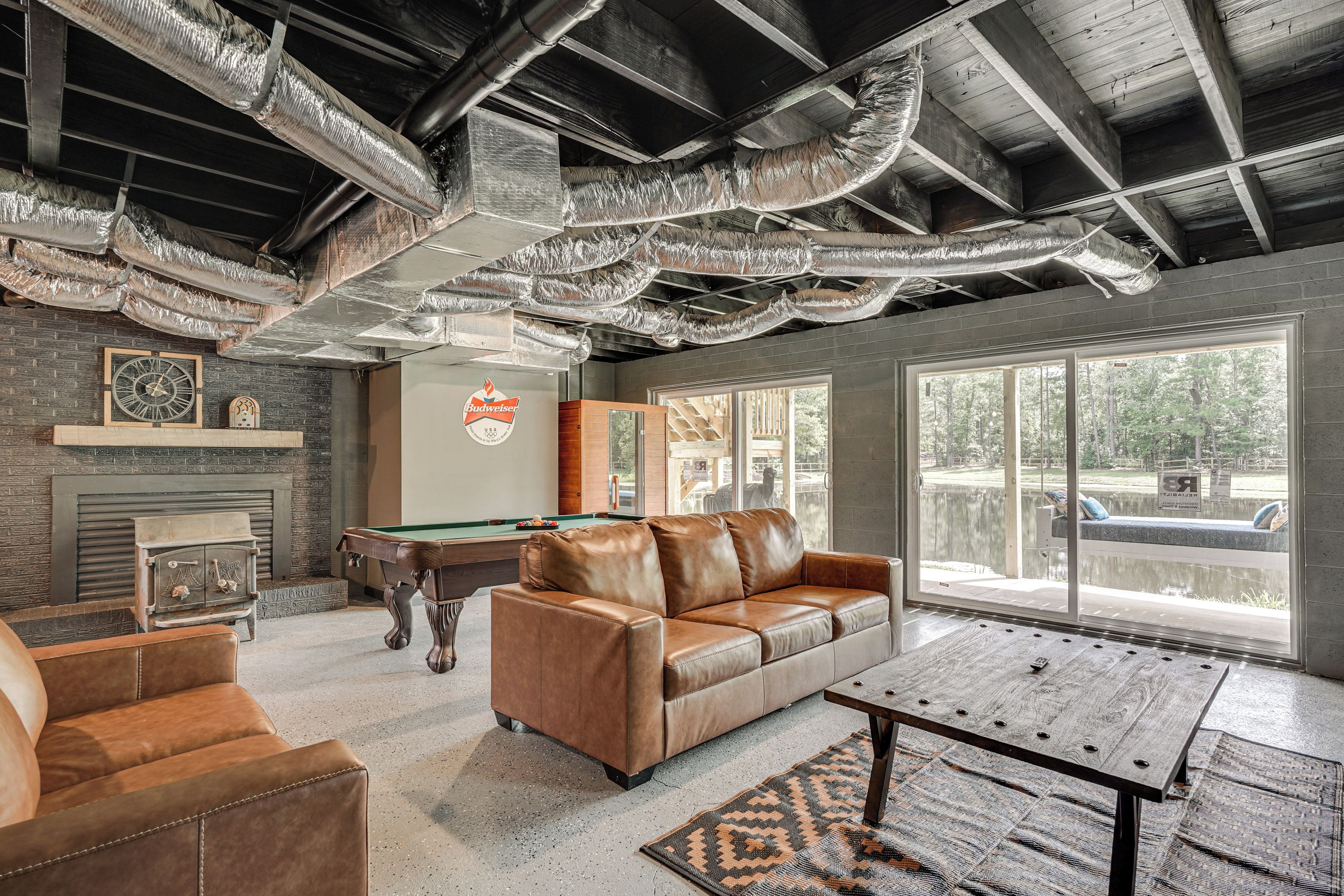 A spacious room with a pool table, leather sofa, and a fireplace.