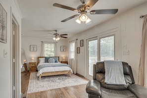 A bedroom with a bed, a chair, a ceiling fan, and a large window. - Waterfront Retreat Near Masters Hot Tub & Sauna (Harlem)