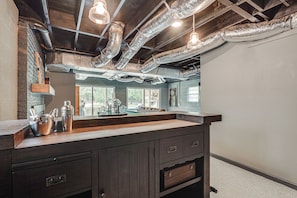 A modern kitchen with a dark wood countertop, stainless steel appliances, and a large window providing a view of the outdoors. - Waterfront Retreat Near Masters Hot Tub & Sauna (Harlem)