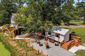 A residential property with a large deck, outdoor seating area, and a small building with a sloped roof. - Waterfront Retreat Near Masters Hot Tub & Sauna (Harlem)