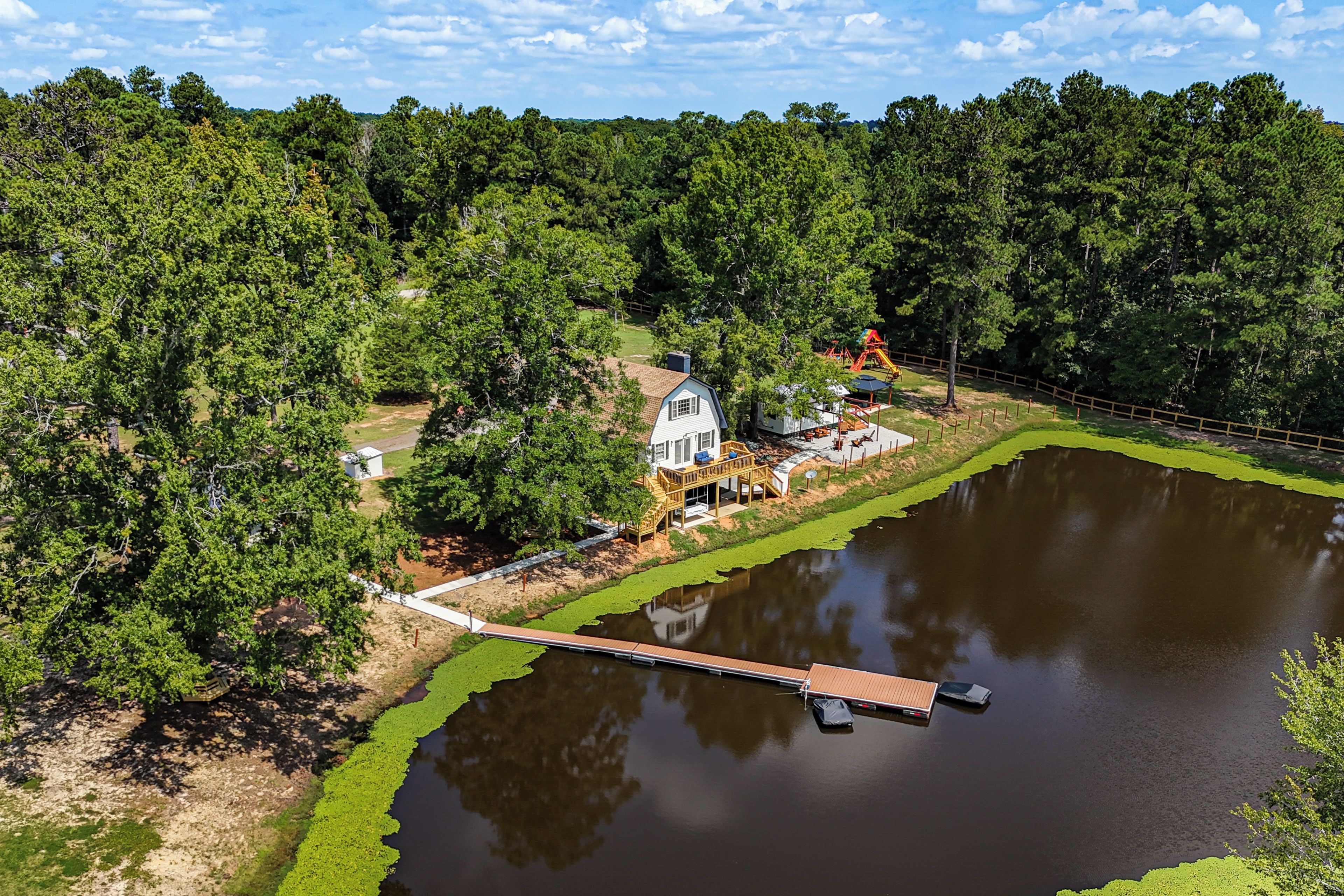 A lakeside property with a dock, a house, and a playground.
