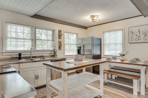 A kitchen with a wooden table, a refrigerator, and a sink. - Waterfront Retreat Near Masters Hot Tub & Sauna (Harlem)