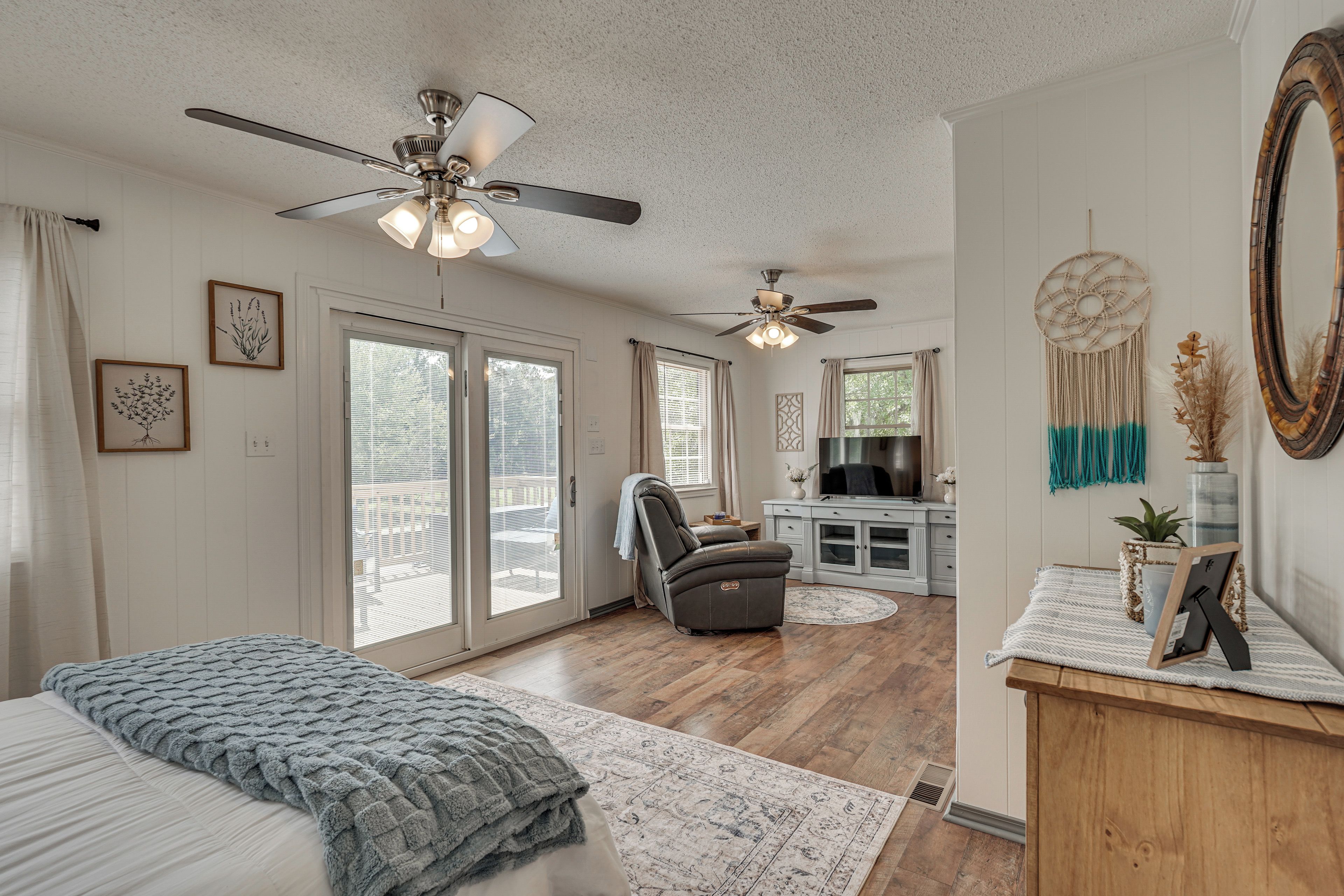 A spacious bedroom with a large bed, a ceiling fan, and a view of the outdoors through the sliding glass doors.