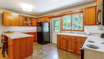 A kitchen with wooden cabinets, a black refrigerator, a sink, and a stove.