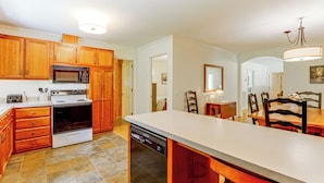 A kitchen with wooden cabinets, a built-in microwave, stove, and dishwasher. - Creekside Cottage: Kayak, Tube, Fish, Remote Work (Dugspur)