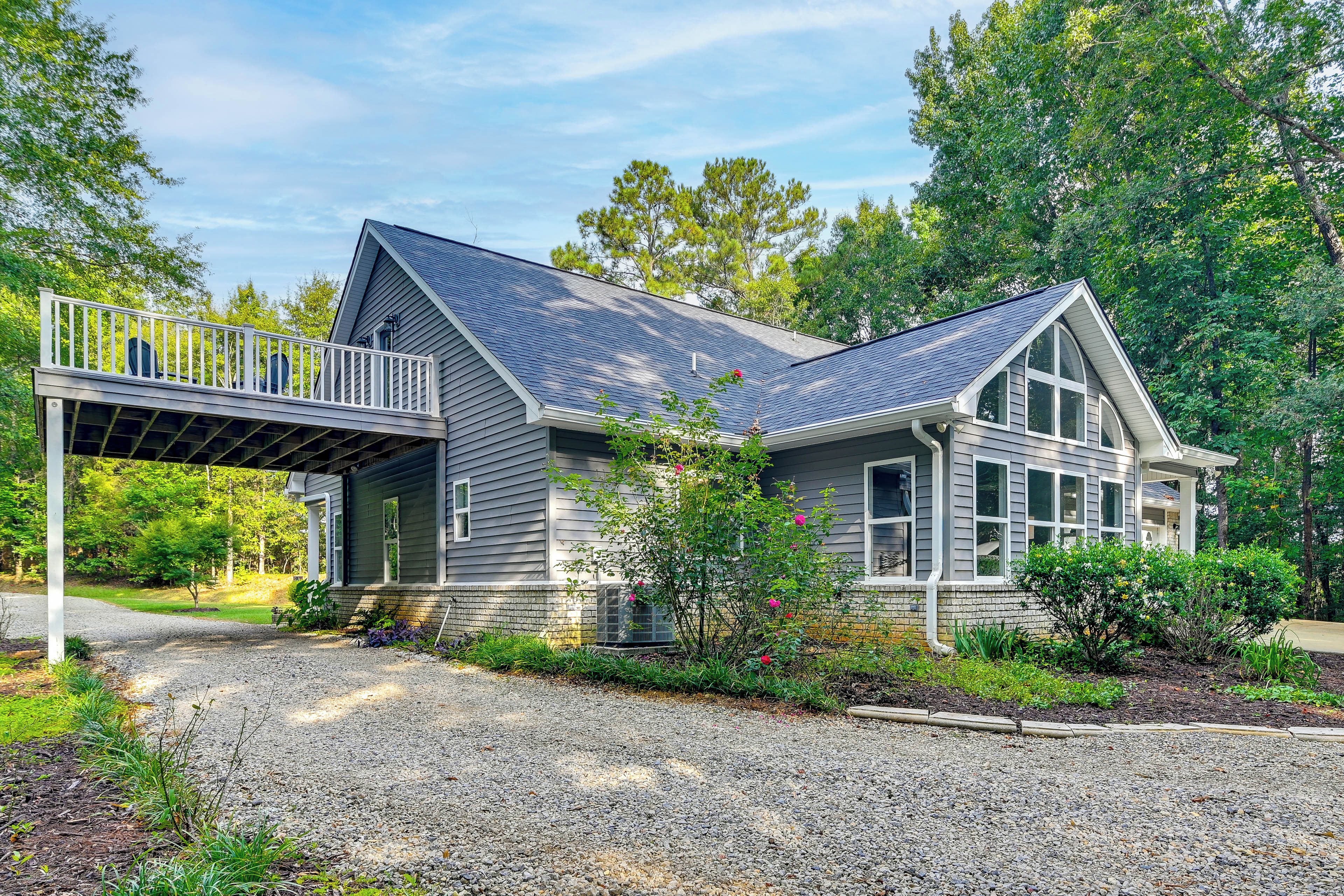 A two-story house with a covered porch and a gravel driveway.