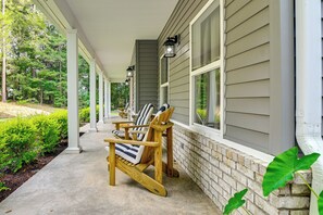 Ein überdachter Balkon mit Holzbänken und einem Tisch, eine Ziegelwand und ein Fenster.
