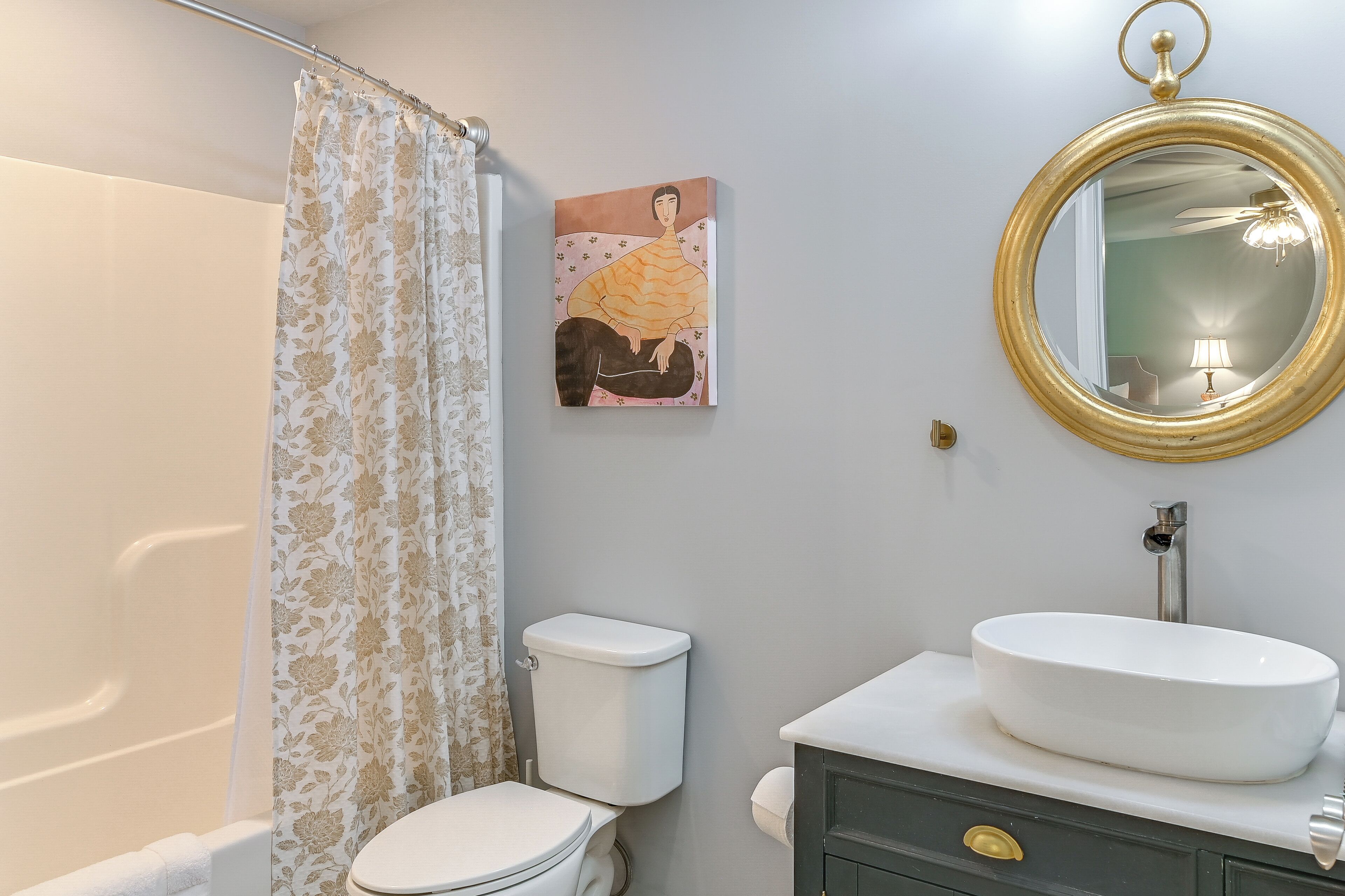 A bathroom with a toilet, a sink, a mirror, and a shower curtain.