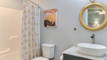A bathroom with a toilet, a sink, a mirror, and a shower curtain.
