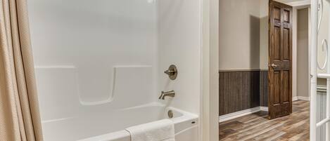 Un baño con bañera, toalla y puerta de madera.