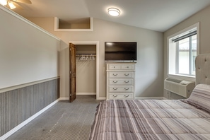 A bedroom with a bed, a dresser, a television, and a window.