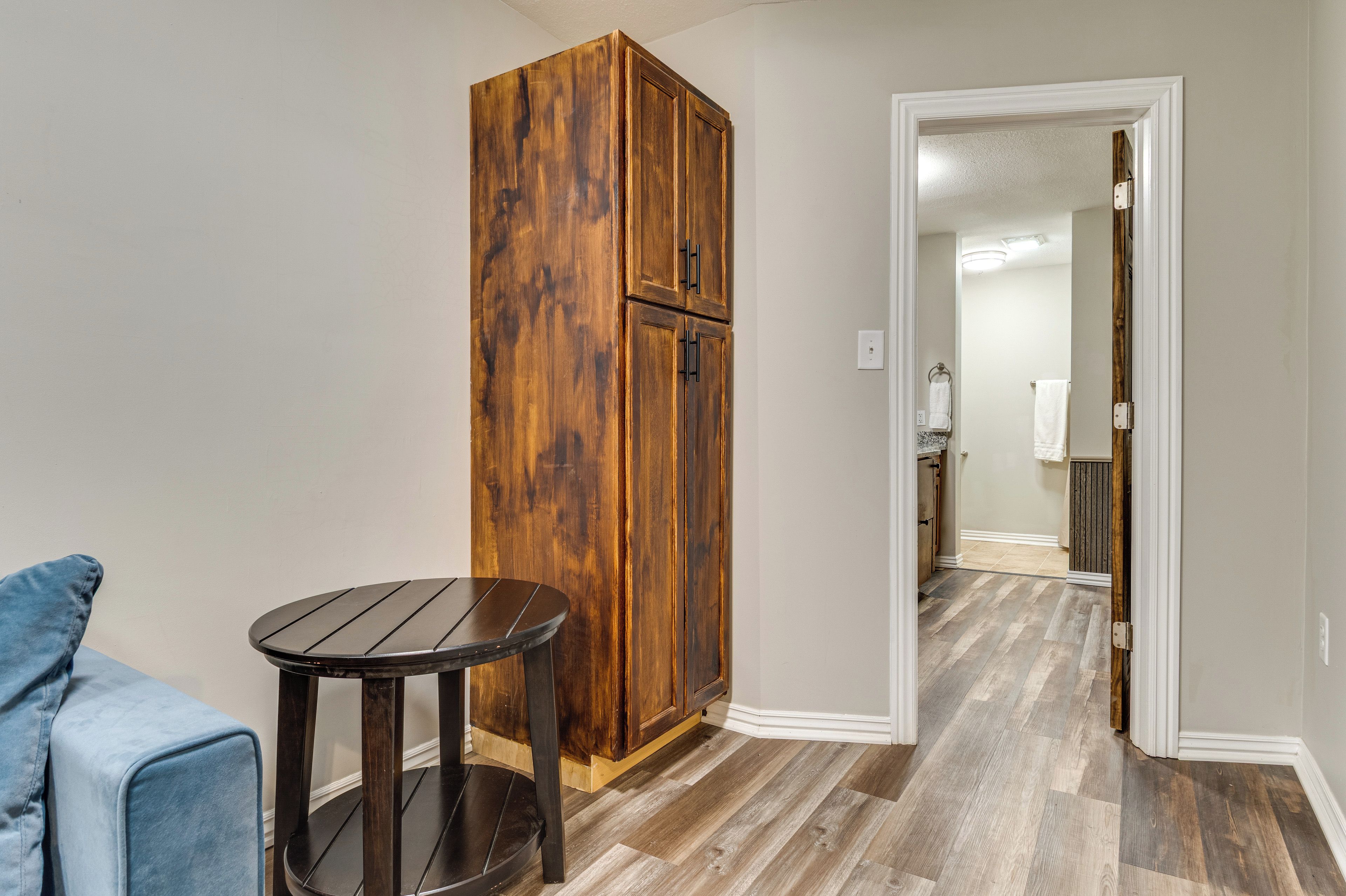 A room with a wooden wardrobe, a round table, and a blue chair.