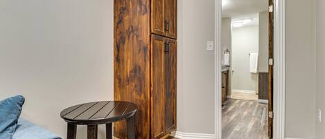 A room with a wooden wardrobe, a round table, and a blue chair.