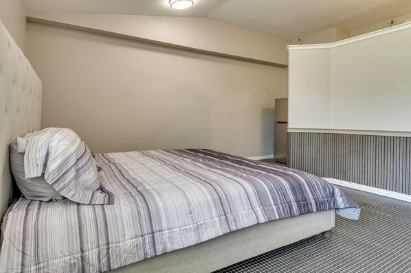 A bedroom with a bed, a headboard, a wall-mounted TV, and a wooden panel wall.