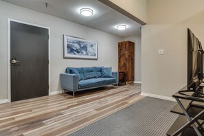 A modern living room with a grey sofa, a wooden cabinet, and a framed abstract painting on the wall.