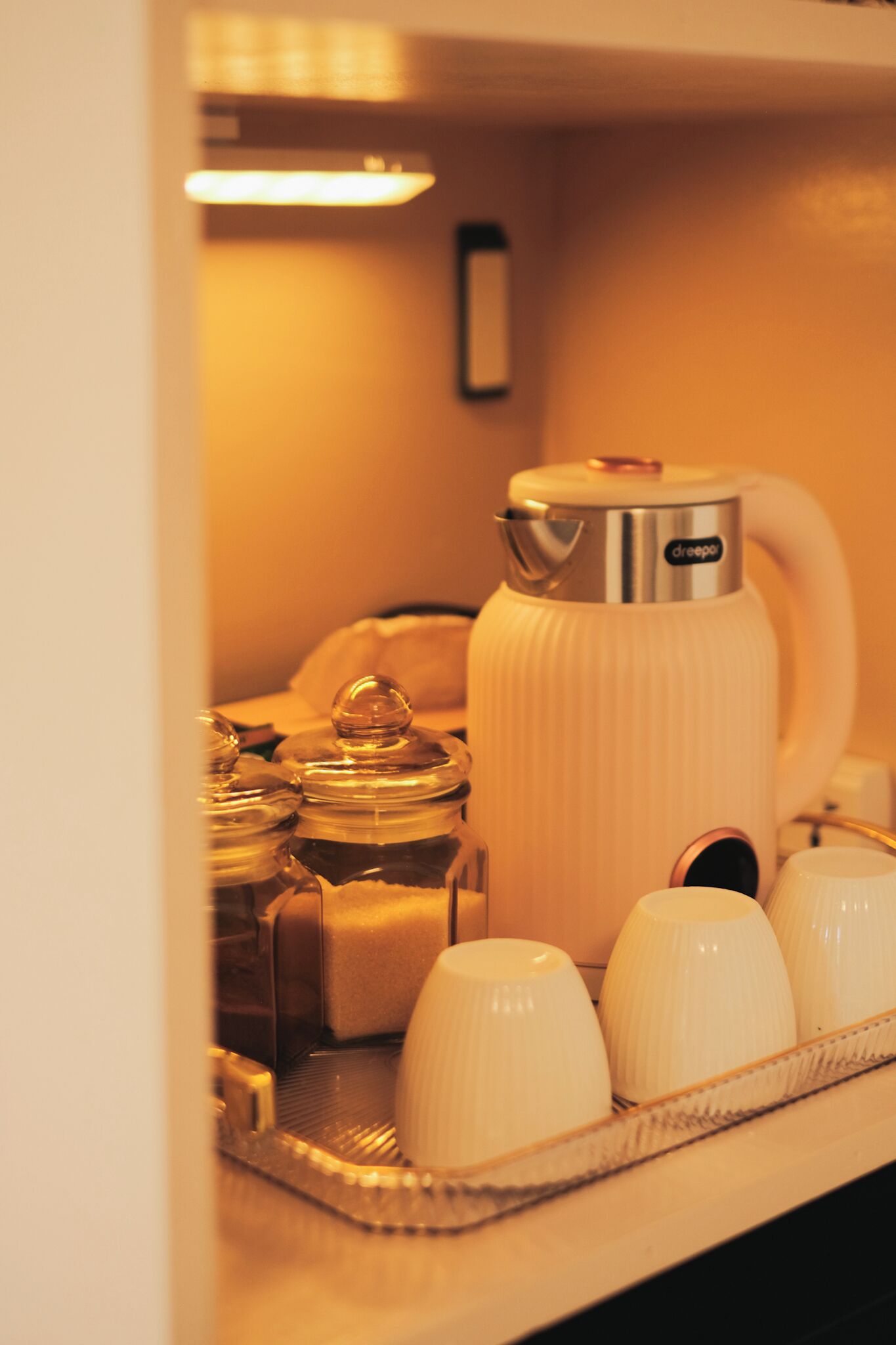 Een koffieapparaat met een filterkoffiezetter, een dienblad met kopjes en een suikerpot.