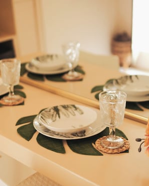 Una mesa de comedor con platos, vasos y un posavasos decorado con una hoja.