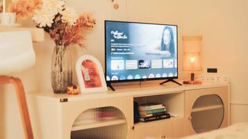 Een televisie op een houten standaard, met een bloevas en een lijst met een foto.