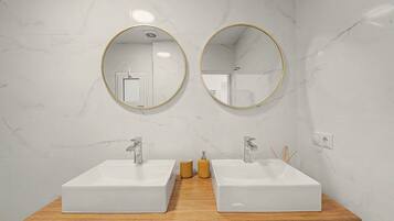 A bathroom with two sinks, each with a modern faucet, and two round mirrors with gold frames.