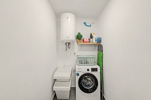 Ein kleines Badezimmer mit Toilette, Waschmaschine und einem Ablagefach für Pflegeartikel.