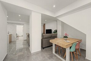 Un interior modern amb zona de menjador, un sofà i una televisió al fons.
