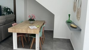 Un comedor con una mesa de madera, sillas, una planta en maceta y una botella verde en un estante.
