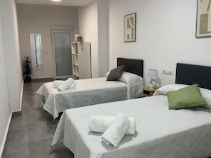 A hotel room with two beds, a small bedside table with a lamp, a potted plant, and a door with a window. - Holiday Home 'Aleda' with Private Terrace and Wi-Fi (Cuevas del Becerro)