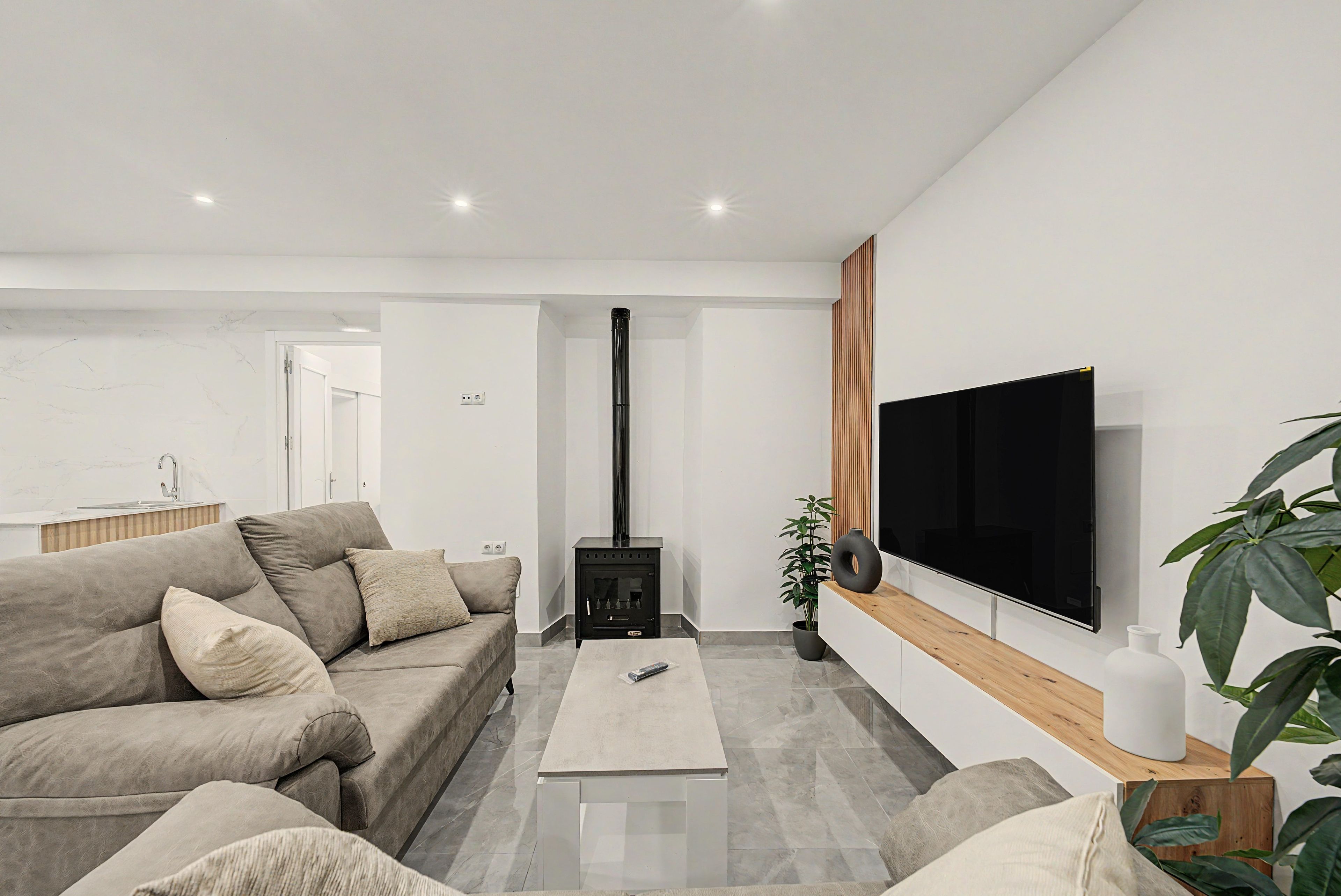 Een moderne woonkamer met een bank, salontafel, televisie en open haard.
