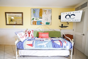 A bedroom with a bed, a wall-mounted TV, a framed picture, and a door with a sign. - 4201 Coastal Highway Unit 404 (Ocean City)