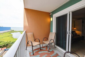 A balcony with two chairs, a patterned rug, and a view of the sea. - 4201 Coastal Highway Unit 404 (Ocean City)