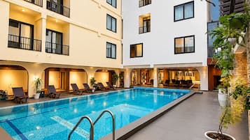Un espace piscine d’hôtel avec une piscine à l’eau cristalline, des chaises longues et une plante en pot.